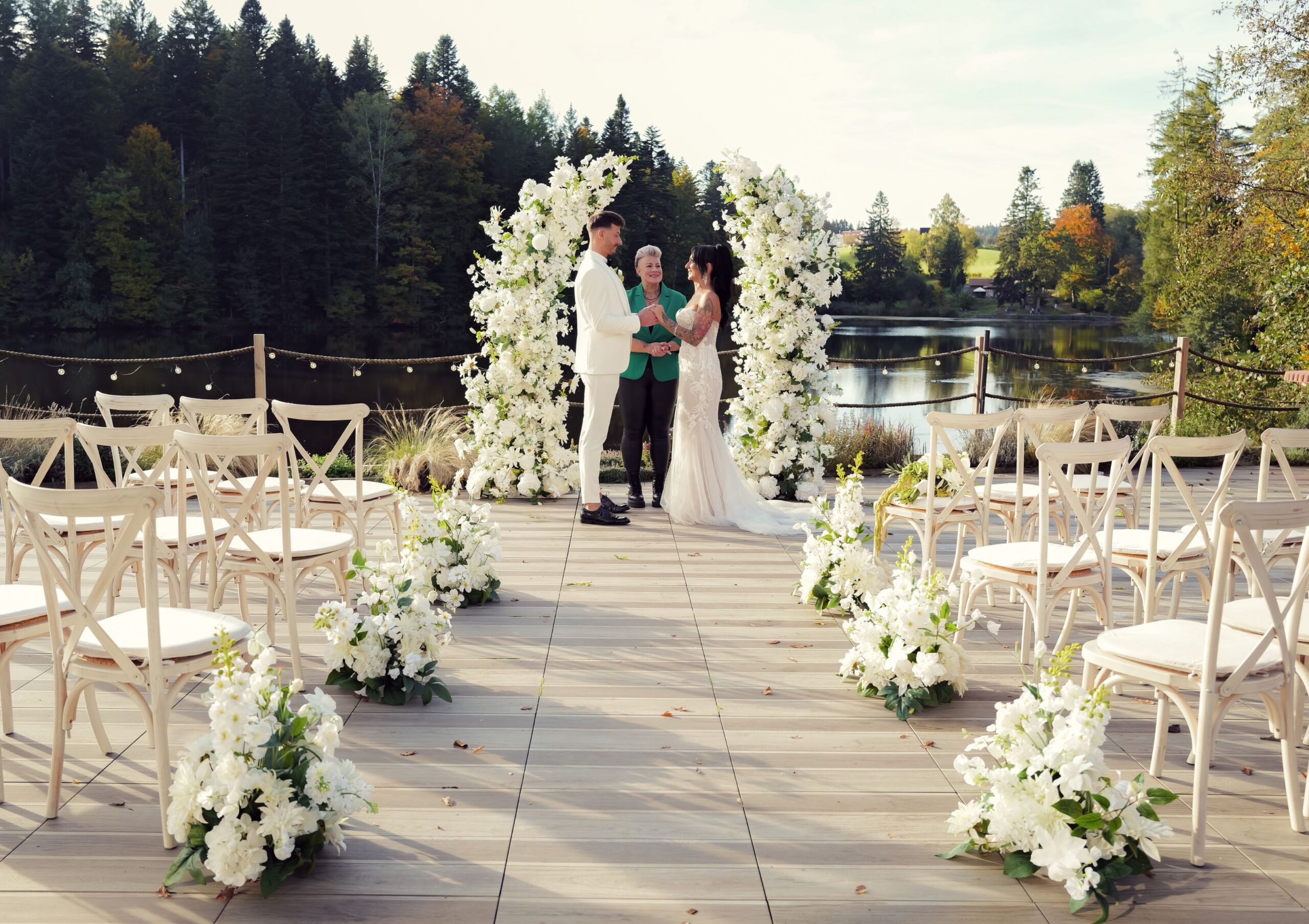 schwaben_resort_ebnisee_hochzeit_galerie_14 Großes, beleuchtetes 'LOVE'-Schild aus Holz steht neben einem festlich gedeckten Tisch mit Blumen, Flaschen und Gläsern, Blick auf einen See im Hintergrund.